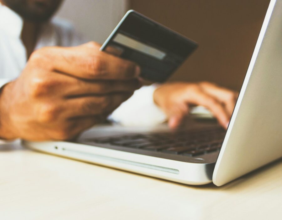 Shopper holding a credit card in front of a laptop
