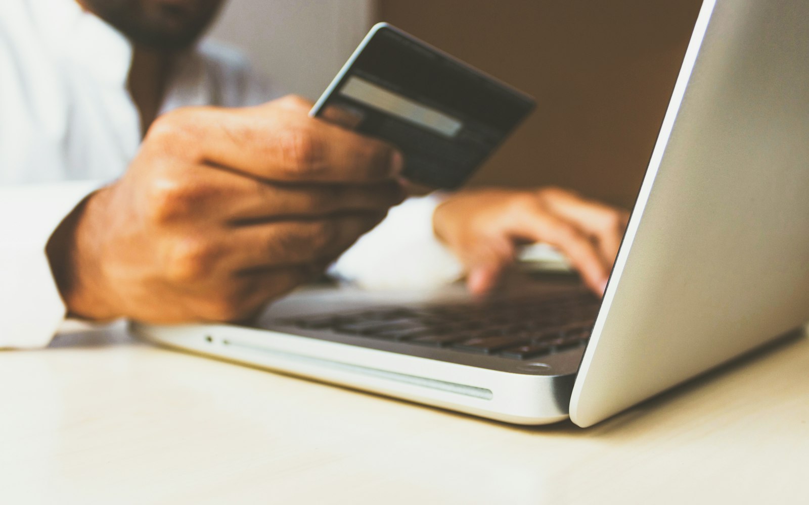 Shopper holding a credit card in front of a laptop